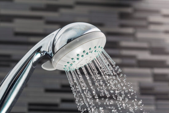 Shower head with water drops falling on a bathroom